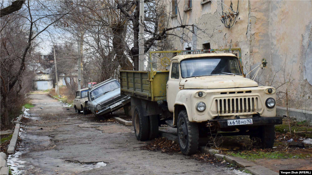 На улице несколько брошенных автомобилей, их потихоньку разбирают на запчасти